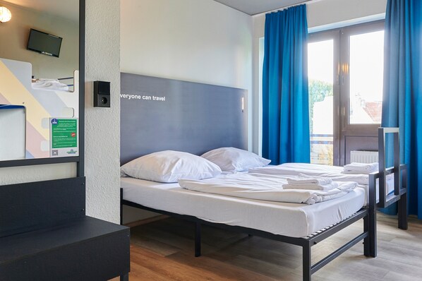 A hotel room with a bed, a desk, a television, and a window with curtains.