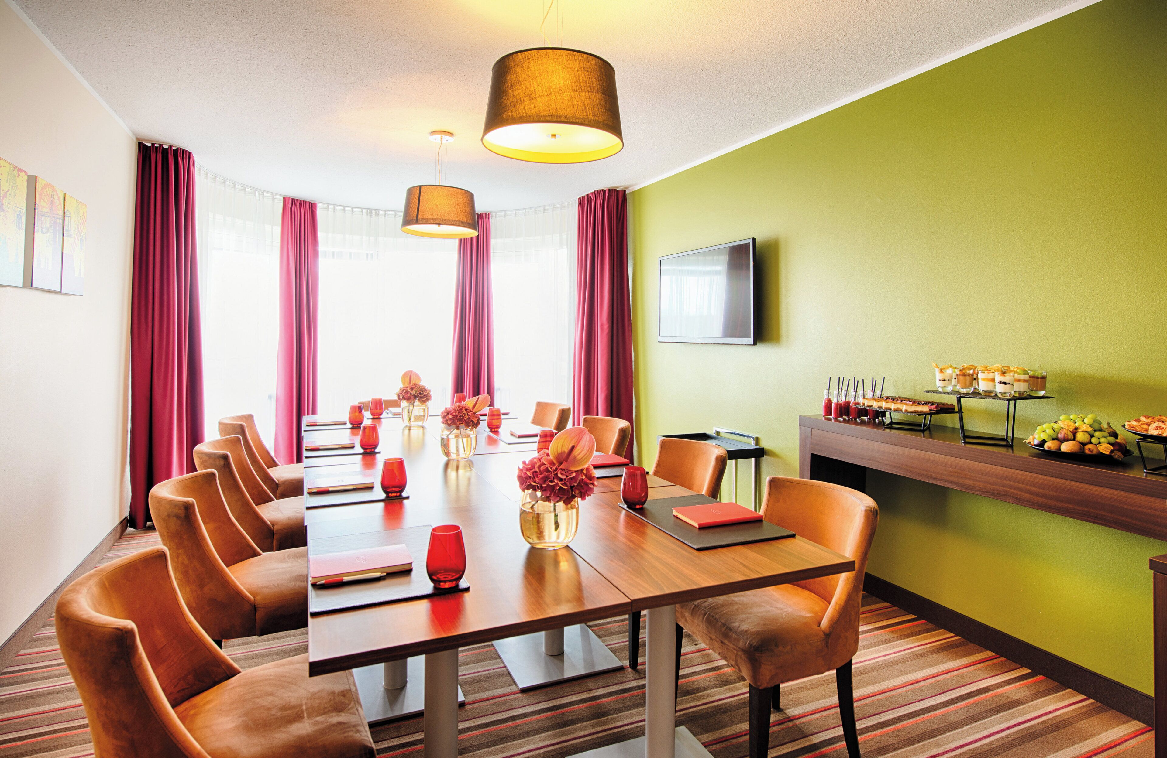 A conference room with a long table, multiple chairs, and a buffet area with food and drinks.