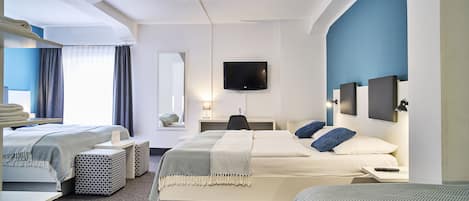 Habitación de hotel con cama, escritorio, silla, televisor y espejo.