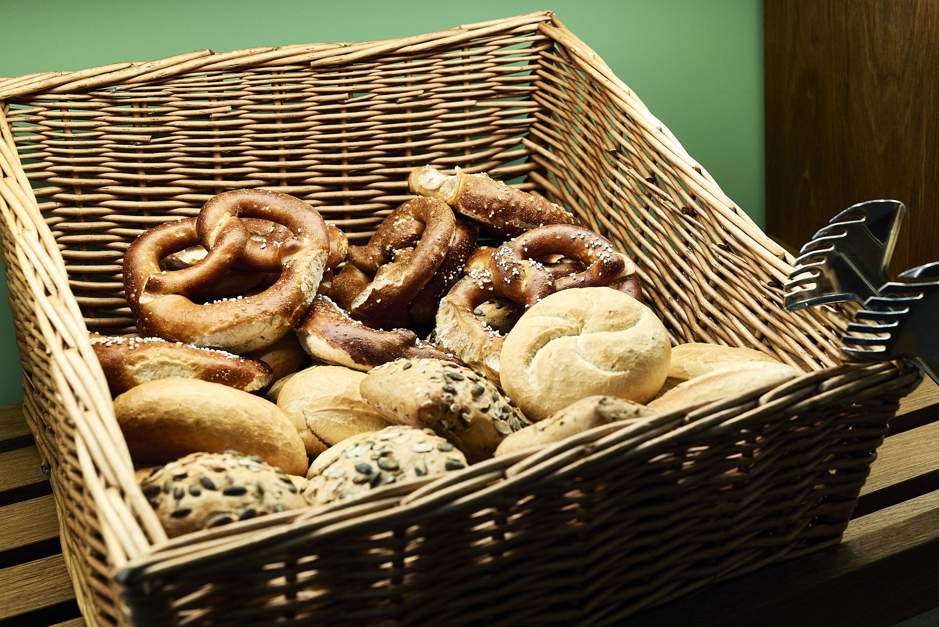 Una cesta de mimbre llena de panes y pretzels varios.