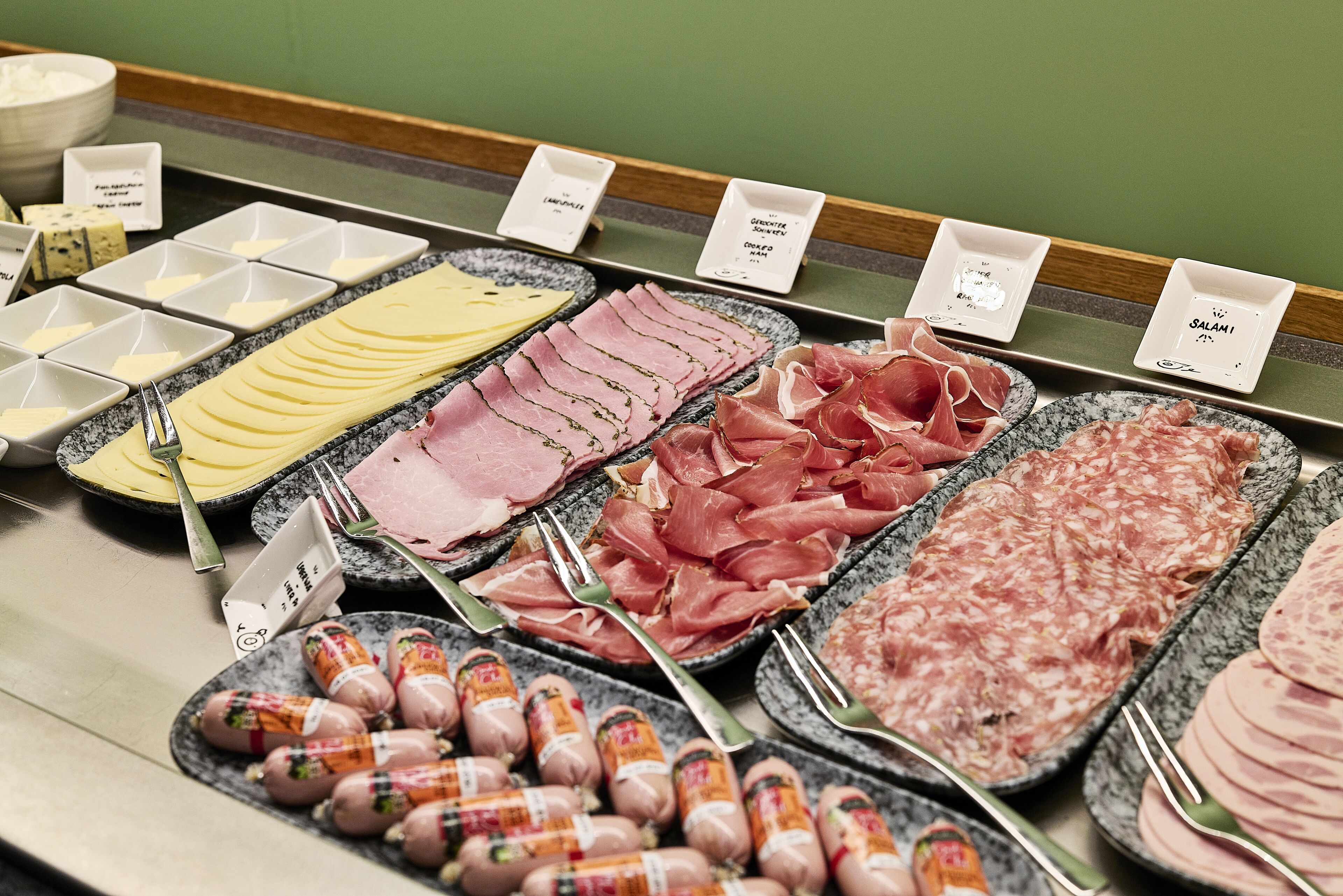 Verschiedene Fleisch- und Käsesorten werden mit Etiketten präsentiert.