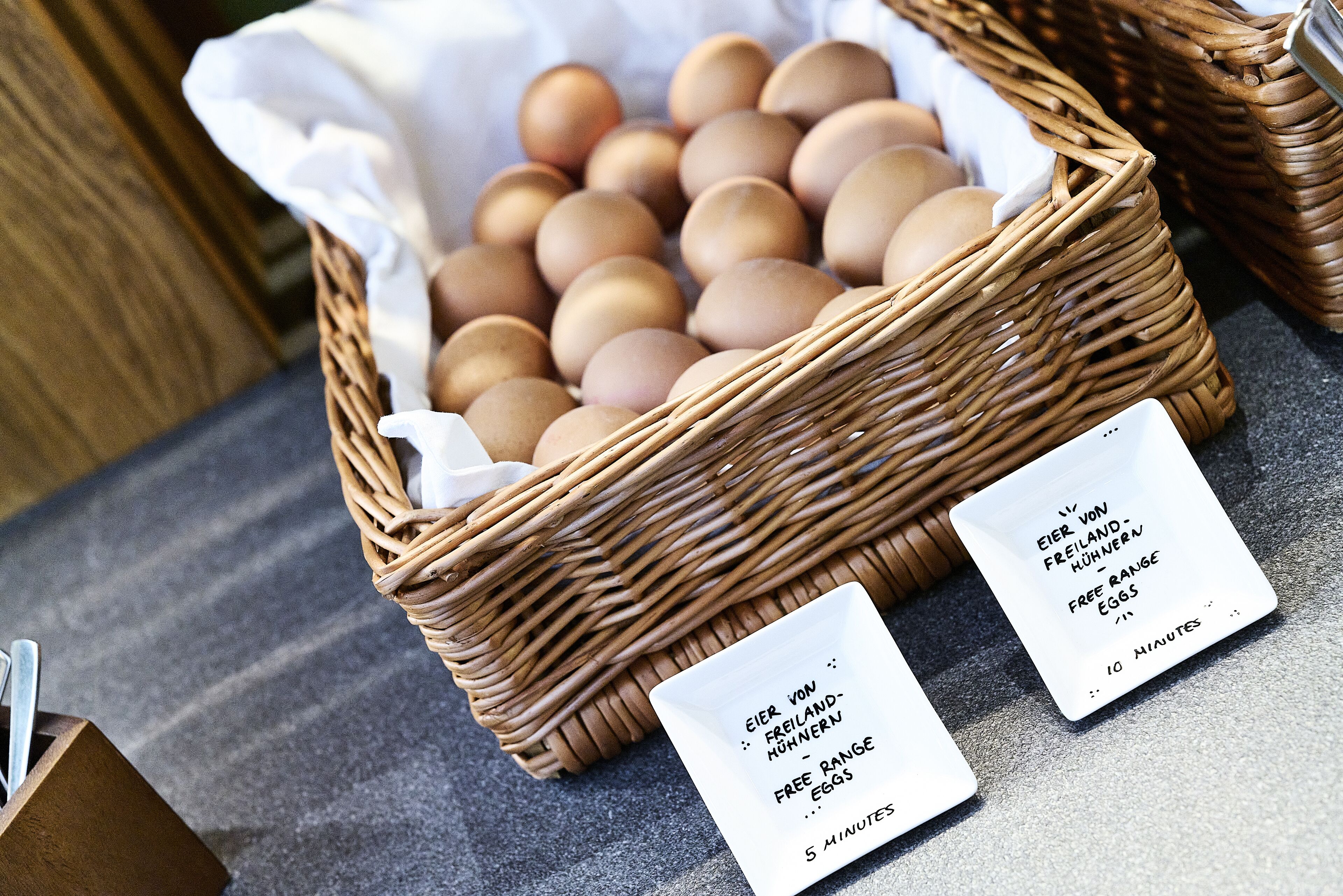 A wicker basket filled with eggs, accompanied by two price tags indicating '5 minutes' and '10 minutes' for free range eggs.