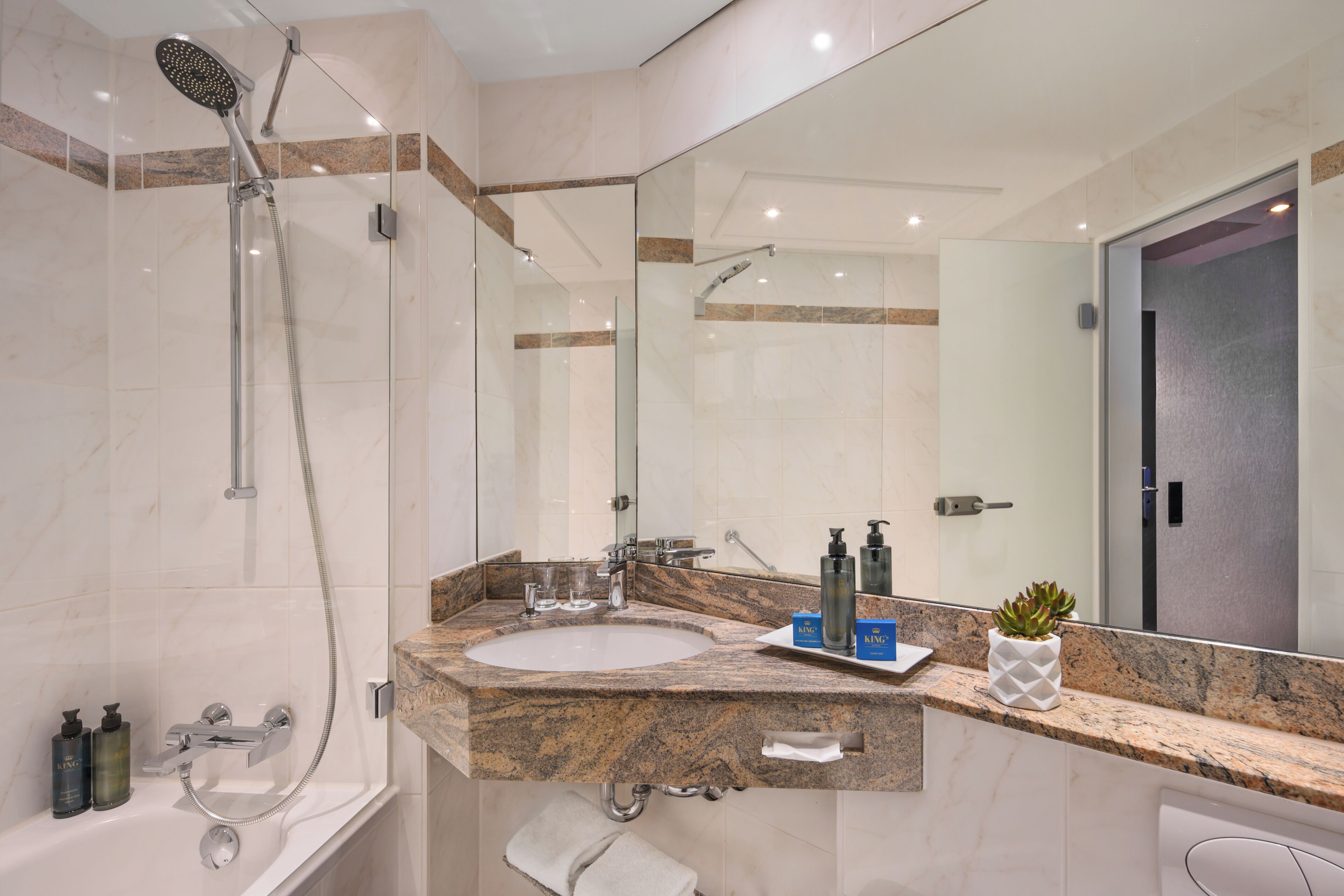 A modern bathroom with a glass-enclosed shower, a marble sink, and a large mirror.