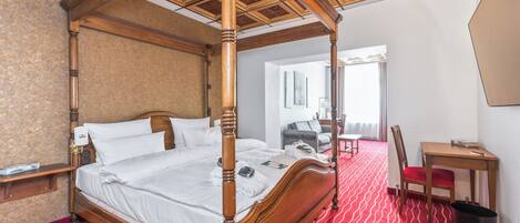 Ein Bett mit Baldachin, ein Holzgestell, ein rot gestreifter Teppich und ein Holztisch mit einem Stuhl.