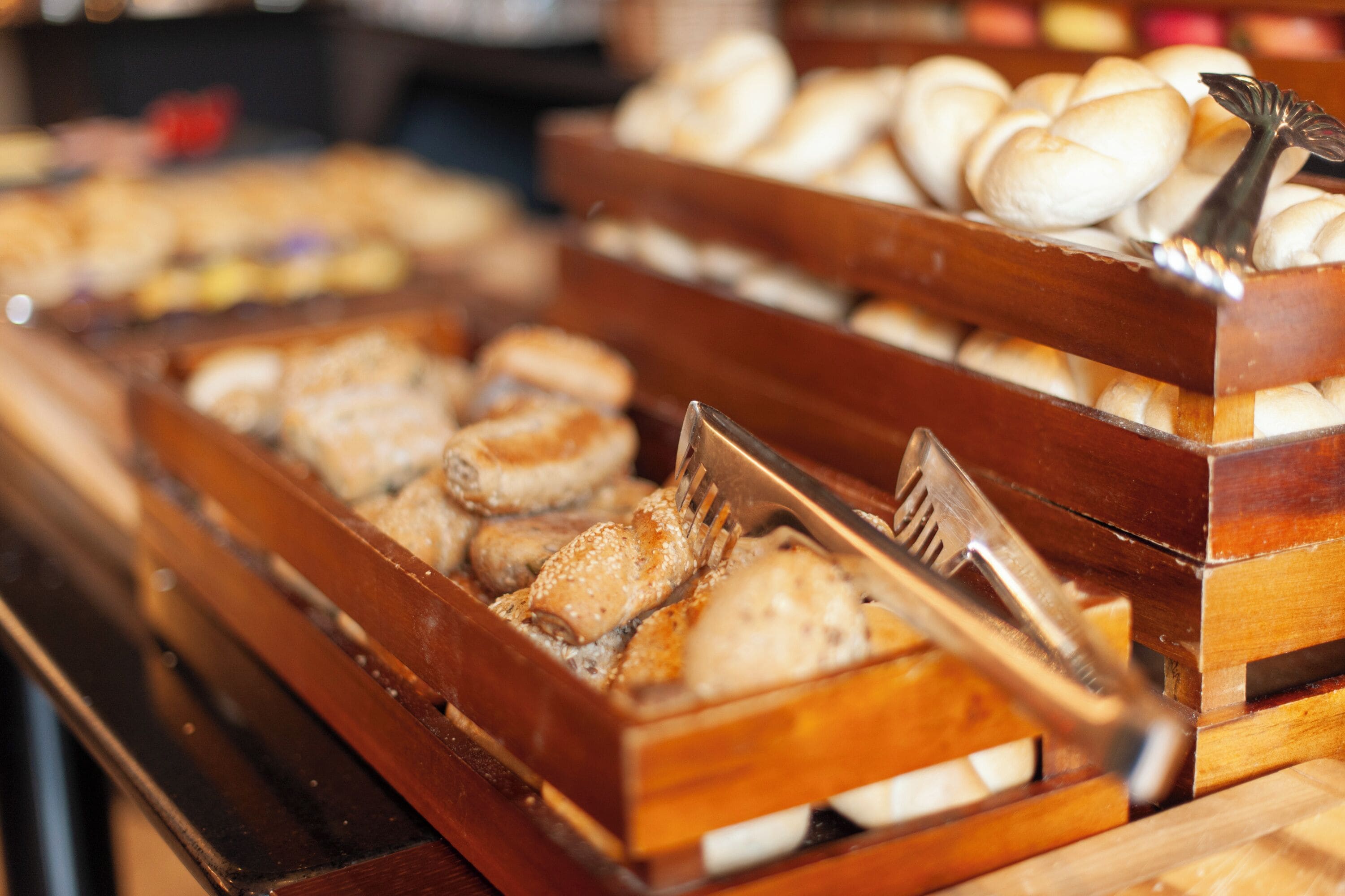 A bakery display with various baked goods in wooden trays.