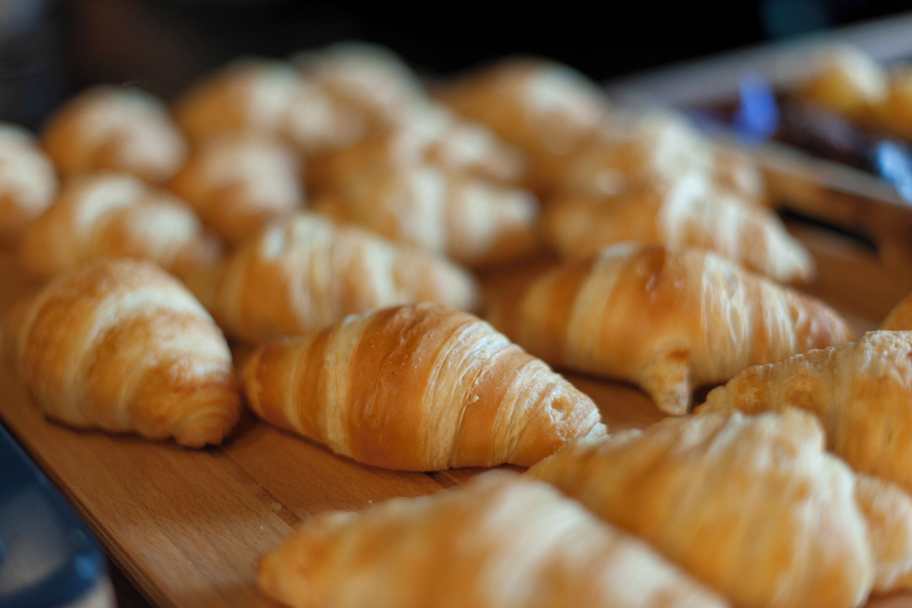 A wooden board with several croissants.