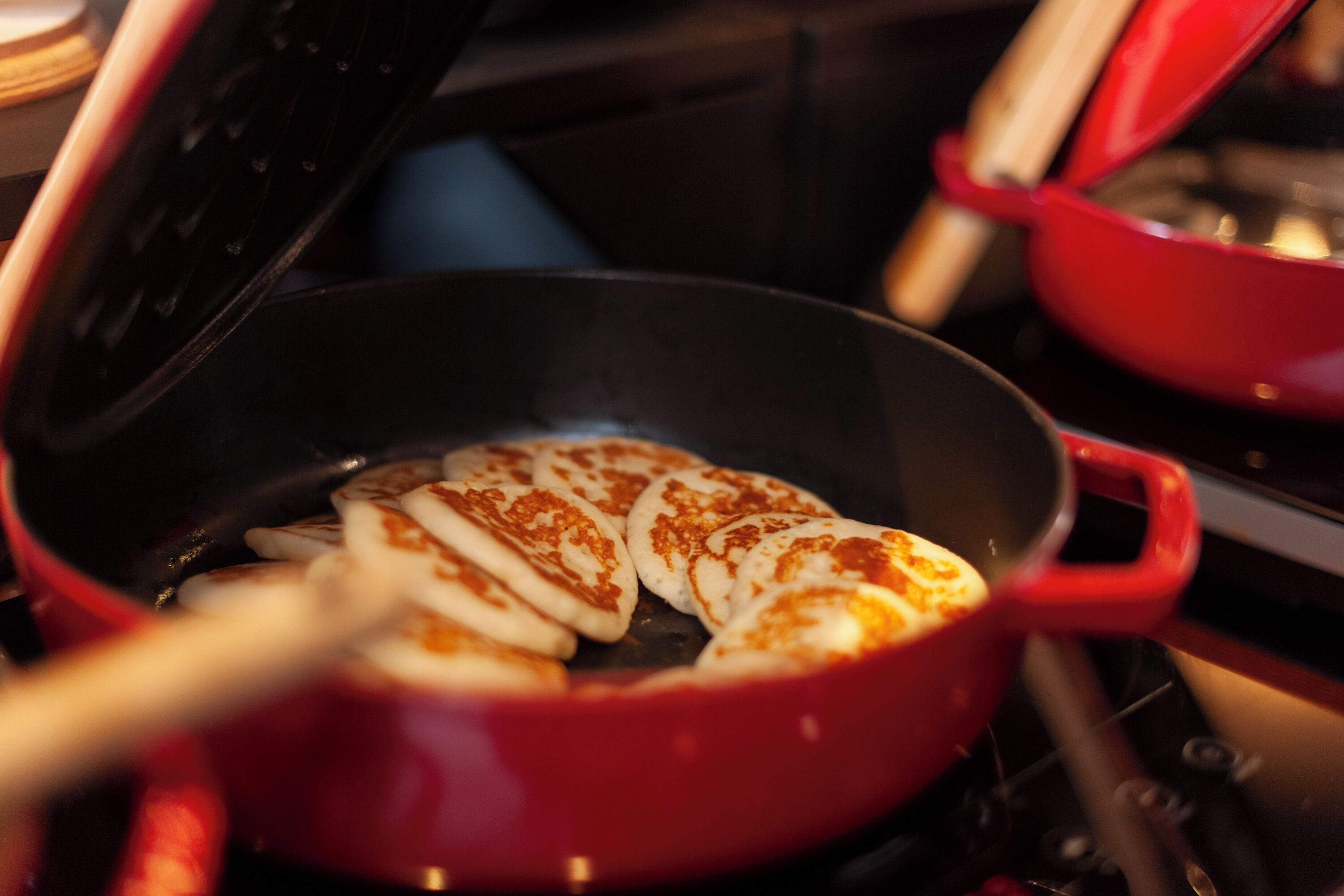 A red pan with food being cooked on a stove.