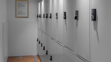 A row of lockers with a tiled floor and a framed notice on the wall.