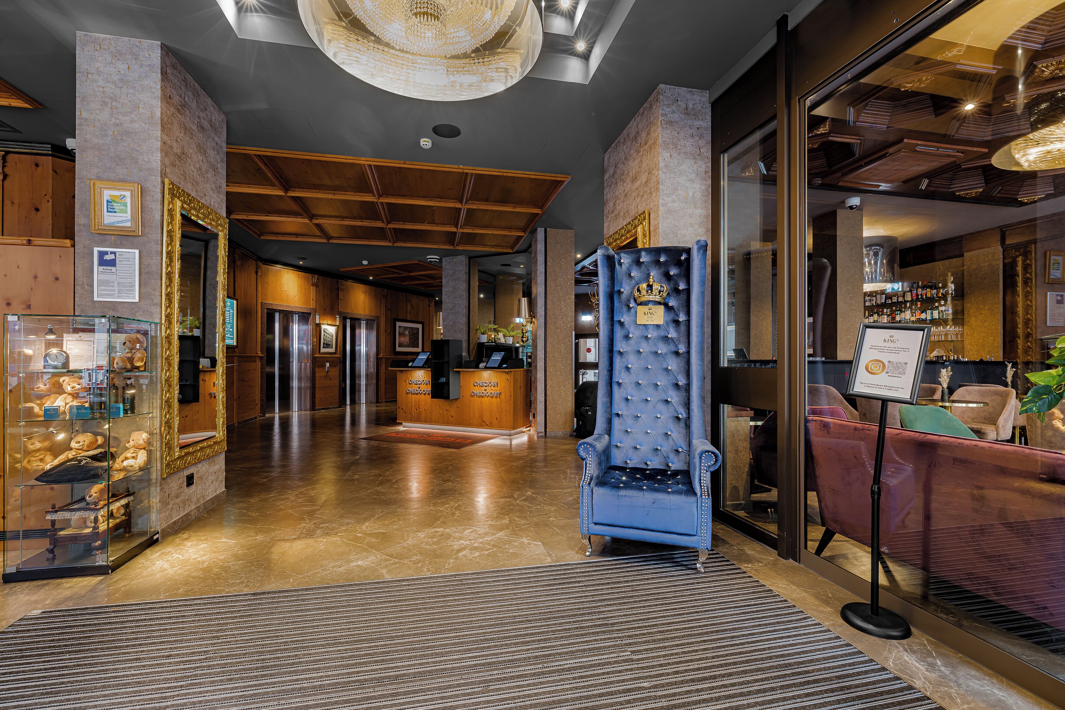 Una hall d'albergo con una reception, una poltrona blu e un'area bar.