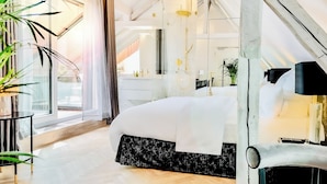 A modern bedroom with a large bed, a vanity, and a large window with curtains. - Boutique Hotel Krone München (Munich)