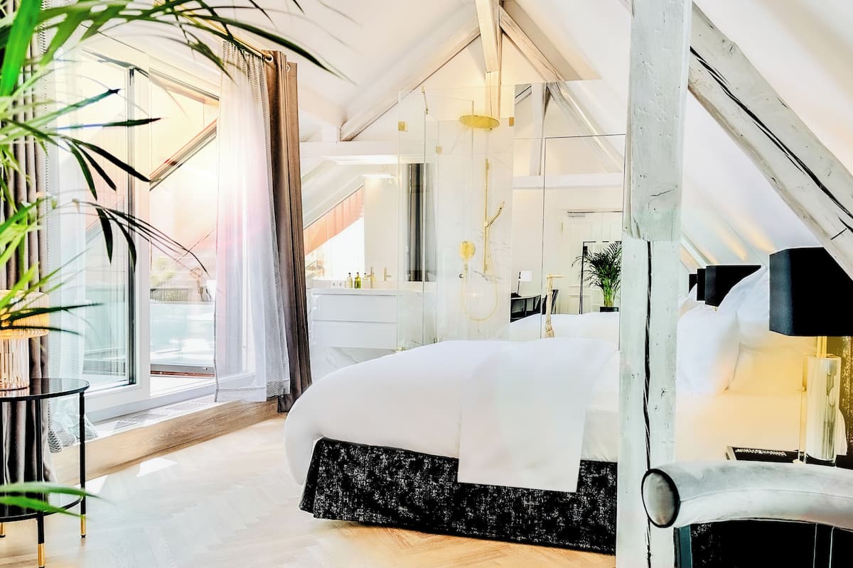 Un dormitorio moderno con una cama grande, un tocador y un ventanal con cortinas.