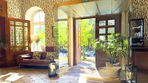 A hotel lobby with patterned wallpaper, a reception desk, a sofa, and a potted plant. - Boutique Hotel Krone München (Munich)