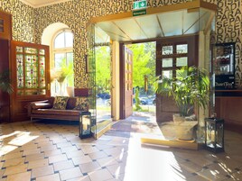Una hall d'albergo con carta da parati decorata, una reception, un divano e una pianta in vaso.