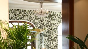 A wooden reception desk with a potted plant, a decorative bird sculpture, and a chandelier. - Boutique Hotel Krone München (Munich)