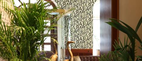 A wooden reception desk with a potted plant, a decorative bird sculpture, and a chandelier.