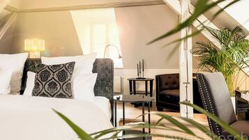 A modern bedroom with a bed, bedside tables, a lamp, a chair, and a potted plant.