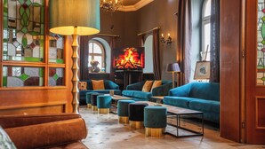 A cozy lounge area with a fireplace, comfortable seating, and a television. - Boutique Hotel Krone München (Munich)