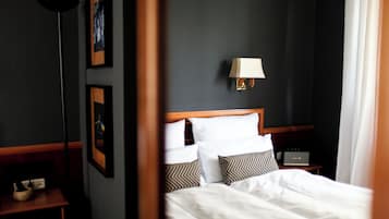 A hotel room with a neatly made bed, a bedside table with a lamp, and framed pictures on the wall.