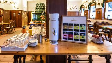 Una barra de desayuno con una cafetera, cristalería y una variedad de productos alimenticios envasados.