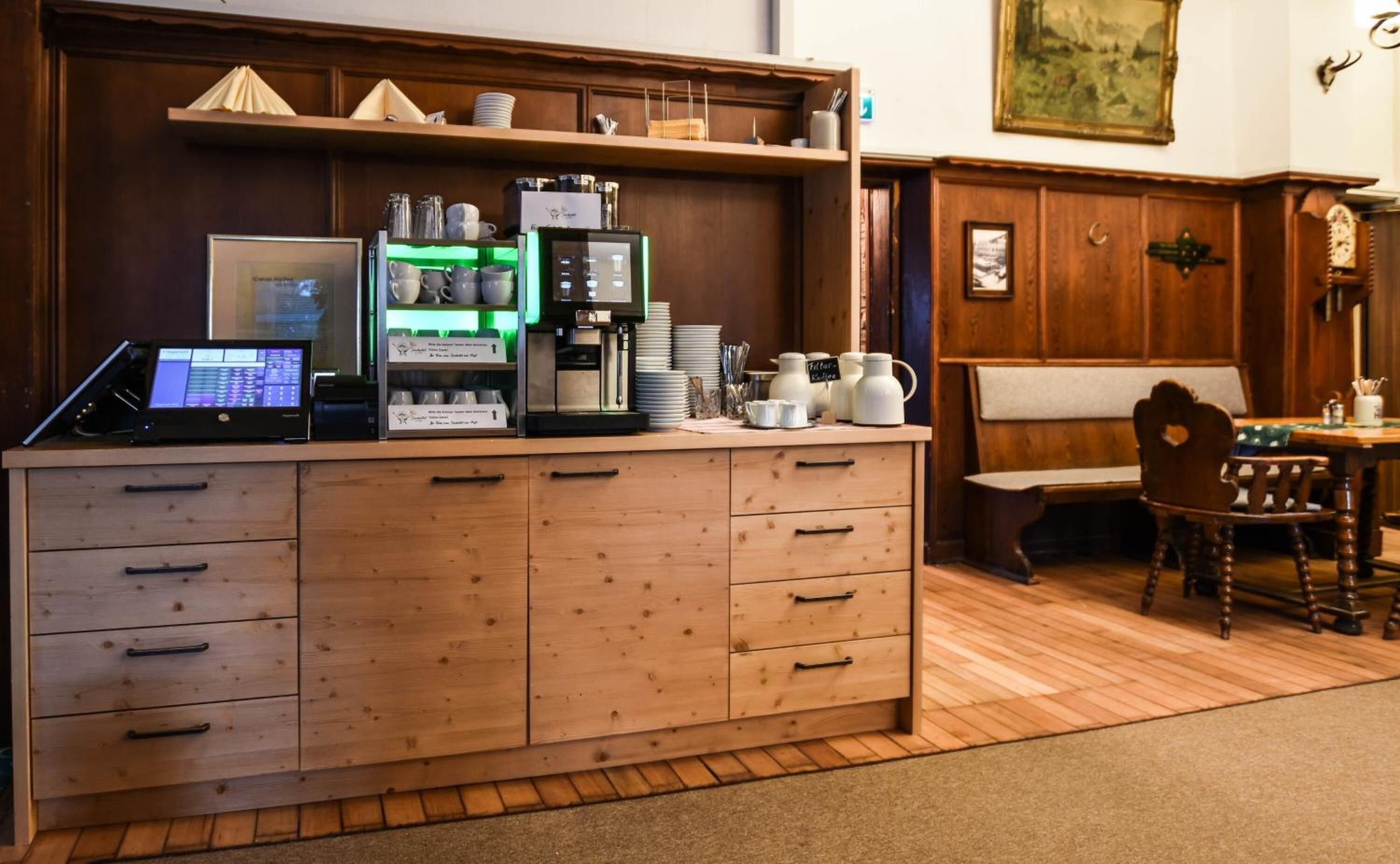Una encimera de madera con una cafetera, una computadora portátil y diversos utensilios de cocina.