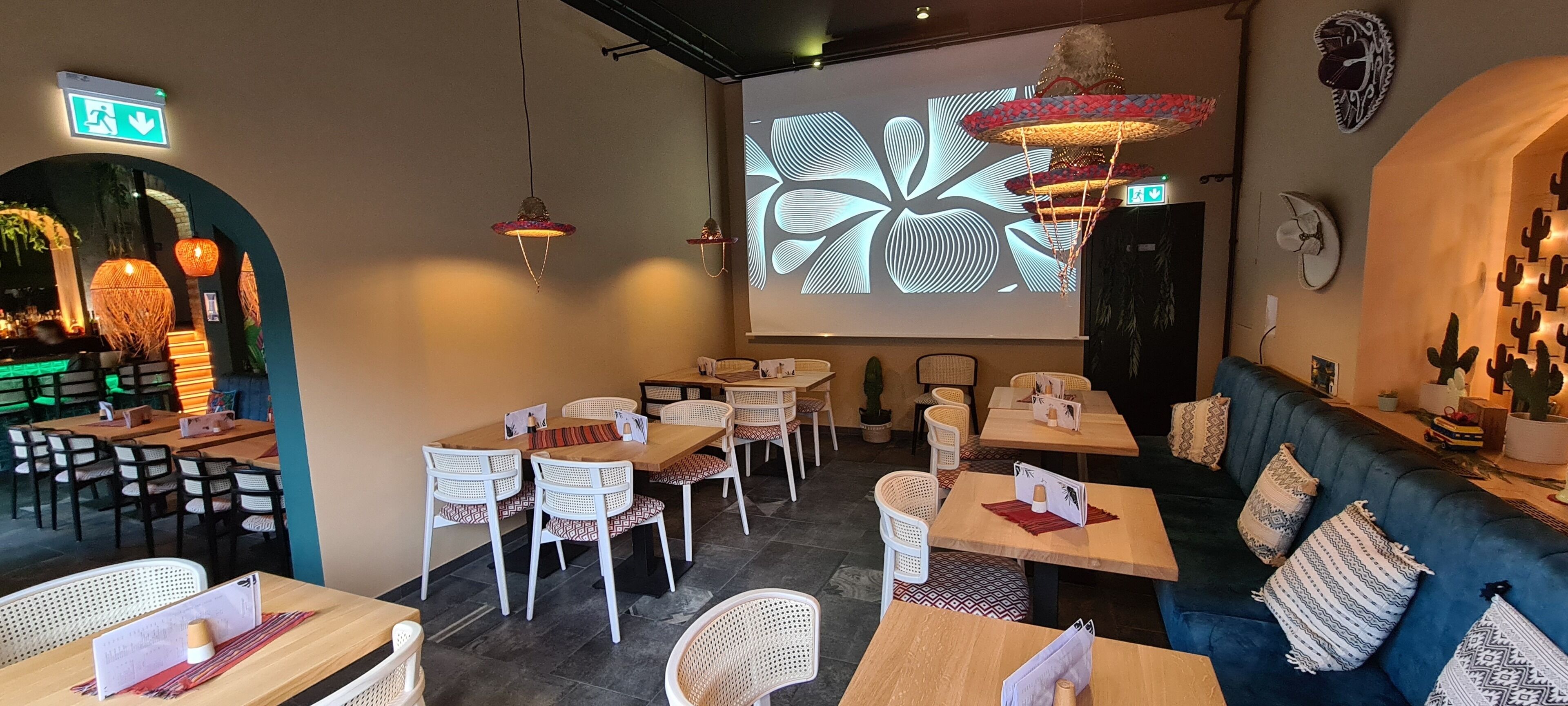 En restaurant med hyggelig indretning, blandt andet træborde og stole, en blå sofa og dekorativ vægkunst.