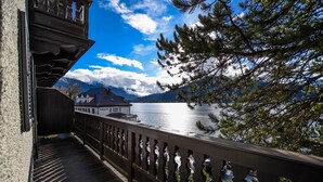 A wooden balcony with a railing overlooking a lake and mountains. - Seehotel zur Post (Tegernsee)