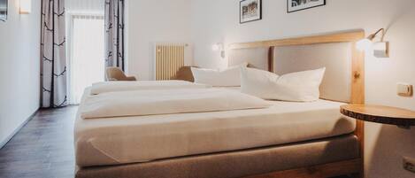 Una habitación de hotel con una cama grande, una silla, una mesita de noche y un radiador.