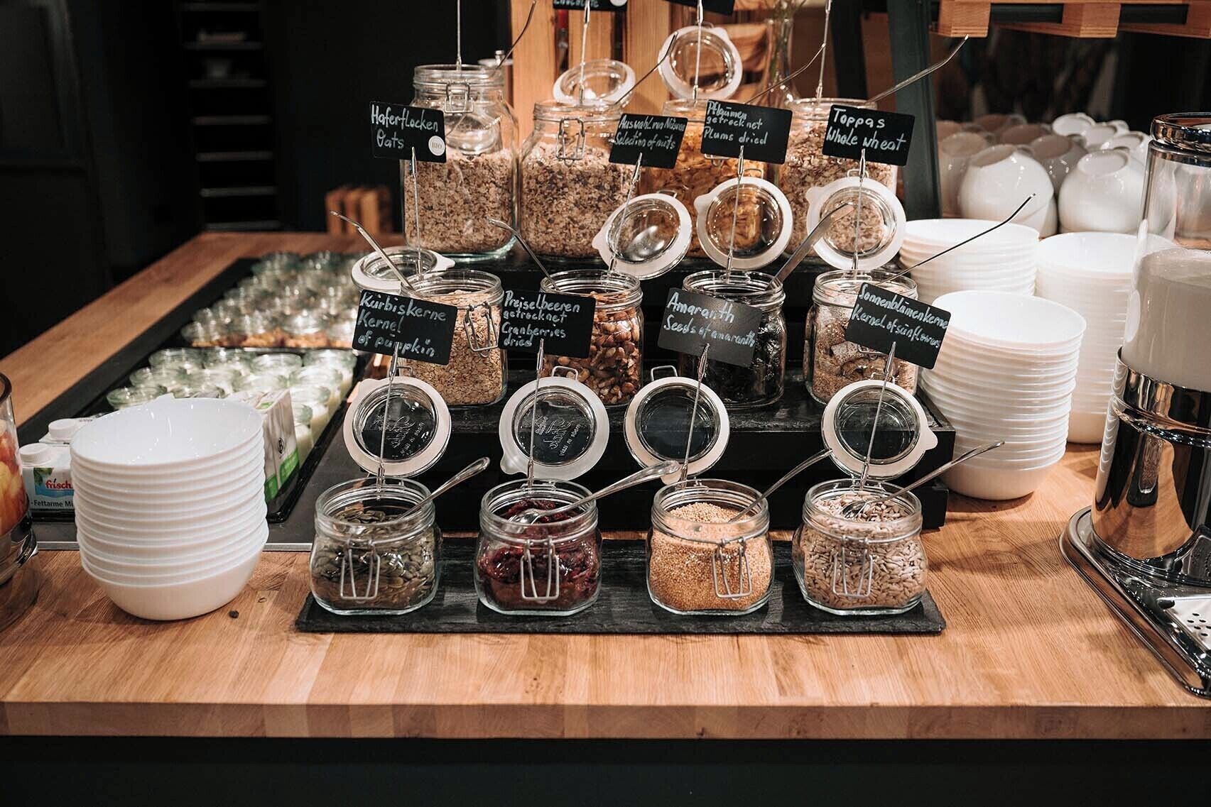 Una exhibición de alimentos con varios frascos etiquetados con ingredientes como avena, ciruelas y calabaza.