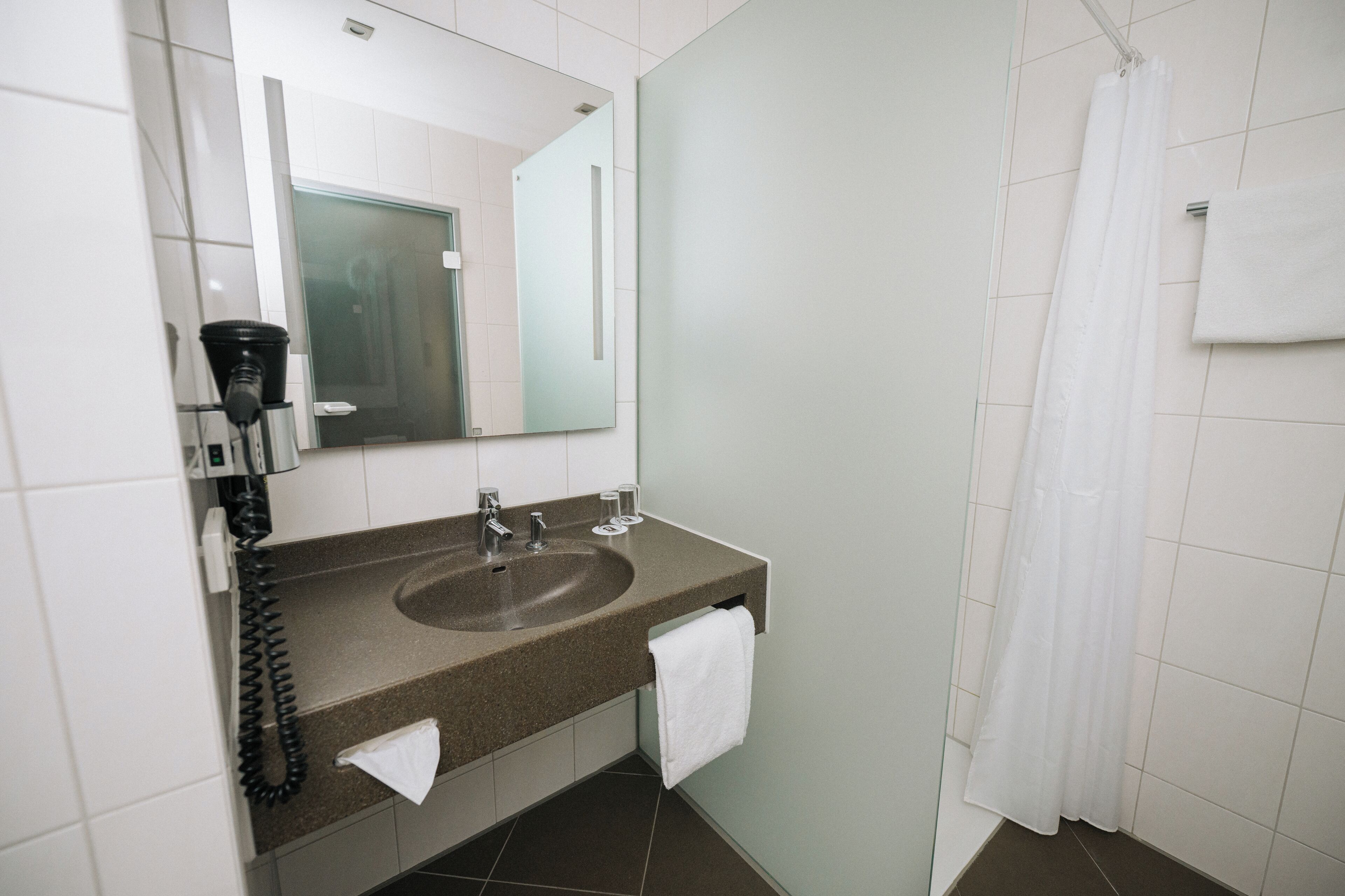 A bathroom with a sink, mirror, and shower curtain.