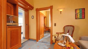 Habitación de hotel con muebles de madera, un televisor, una bandeja de frutas y un cartel en la pared.