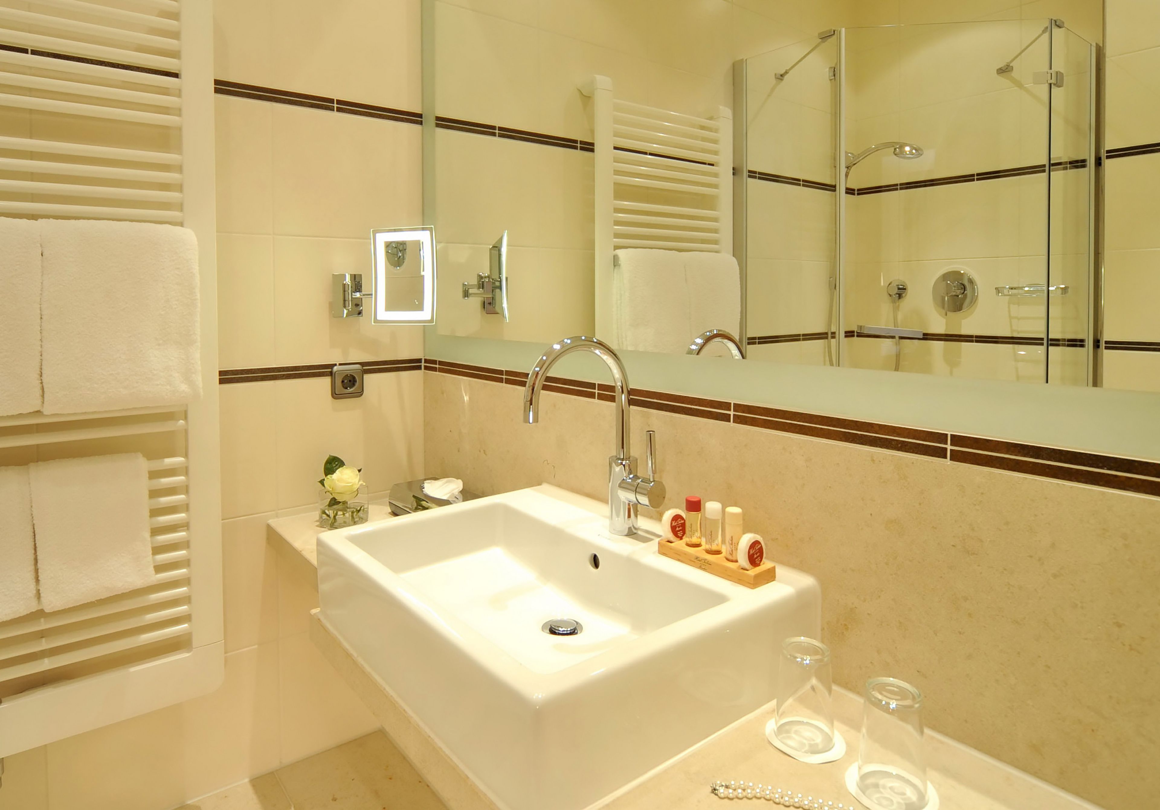 A bathroom with a large sink, a mirror, and a glass shower enclosure.