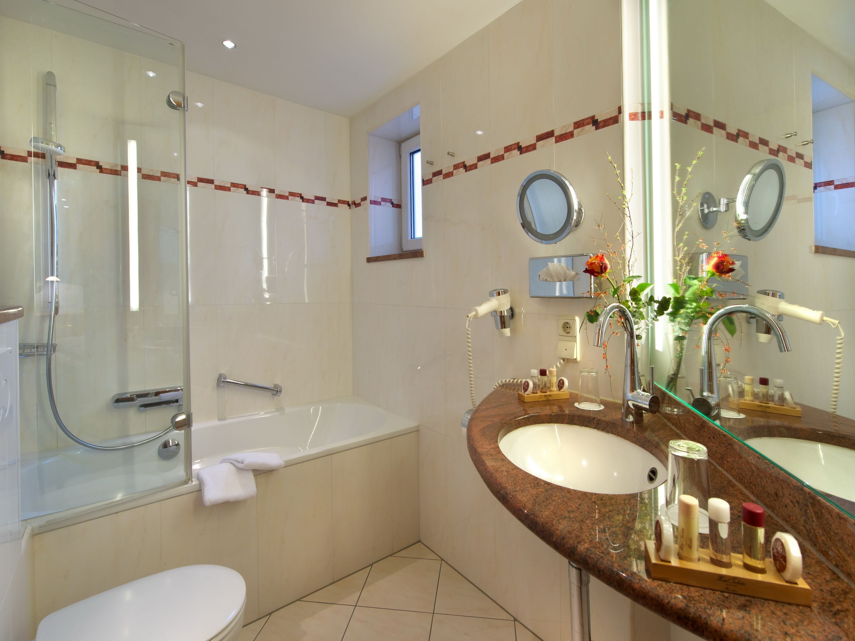 A modern bathroom with a glass-enclosed shower, a standalone bathtub, and a marble vanity with a glass sink.