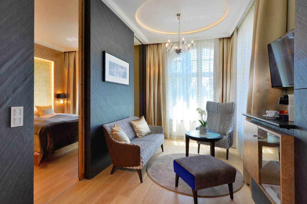 Una habitación de hotel moderna con una cama, un sofá, una mesita y un televisor.