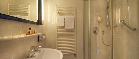 Un baño moderno con ducha envuelta en vidrio, un lavabo blanco y un perchero para toallas.
