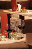 Una mesa de comedor con dos copas de vino, una vela y una rosa.