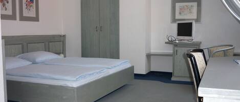 A bedroom with a bed, a desk, a chair, and a wardrobe.