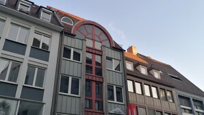 A multi-story building with a prominent red archway, featuring a 'ReSales' store on the ground floor. - Hotel Avenue (Nuremberg)