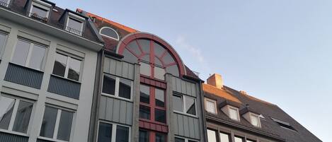 Un edificio de varios pisos con un arco rojo destacado, que cuenta con una tienda 'ReSales' en la planta baja.