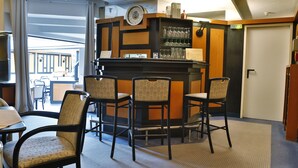 A bar area with four chairs, a counter with glasses, and a clock on the wall. - Hotel Avenue (Nuremberg)