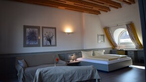 A bedroom with a bed, a desk, and a couch. There are two framed pictures on the wall. - Hotel Avenue (Nuremberg)