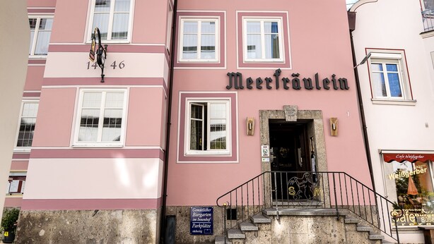A pink building with the name "Meerfräulein" and a staircase leading to the entrance.