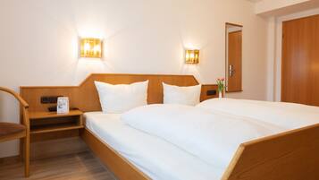 A hotel room with a wooden bed, two bedside tables, a chair, and wall-mounted lights.