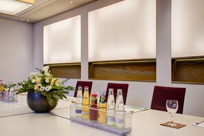 A conference table with a clear bottle holder, a vase of flowers, and a wine glass.
