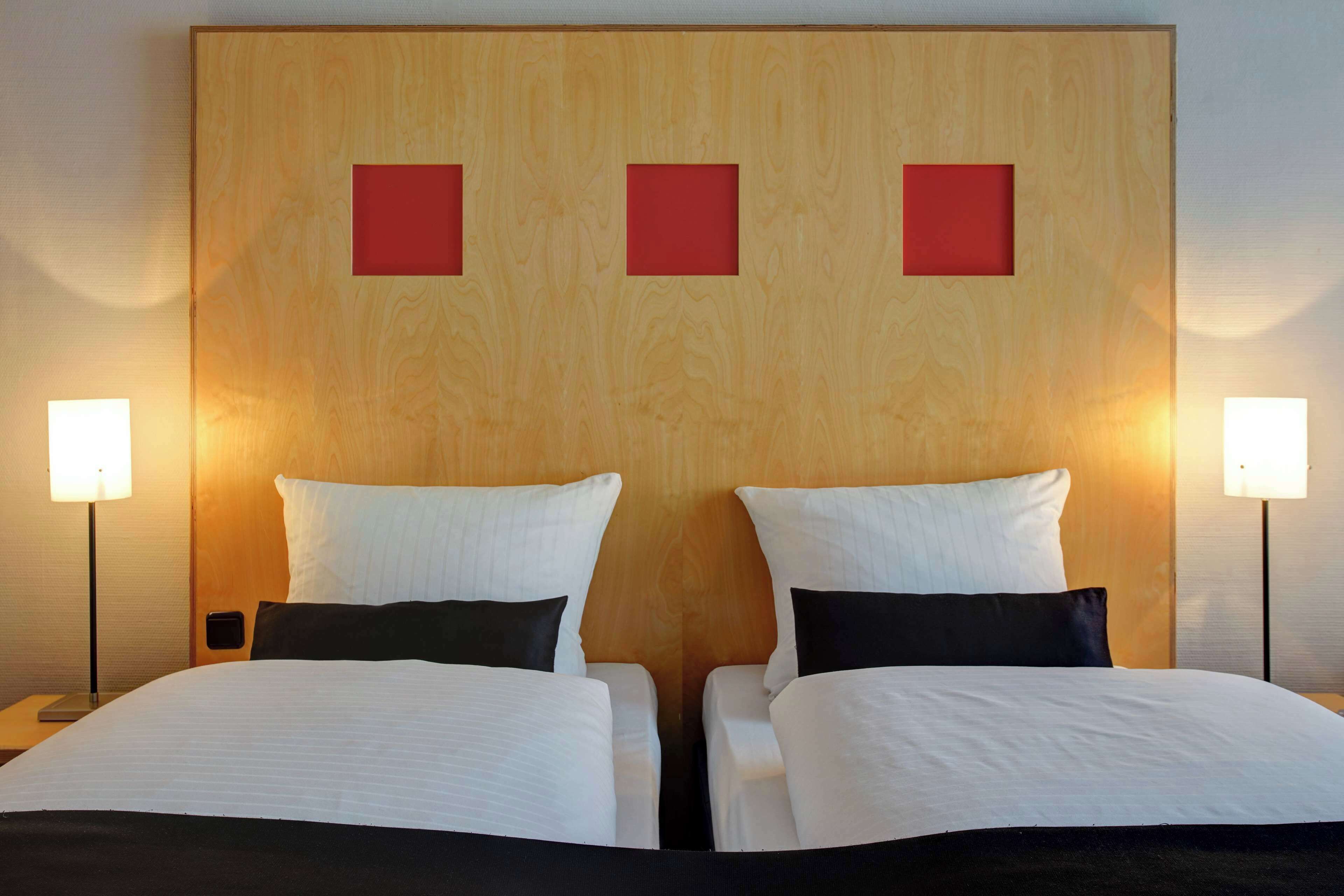 Une chambre d’hôtel avec deux lits, une tête de lit en bois et des lampes de chevet.