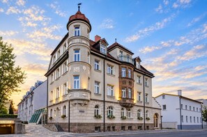 Un edificio histórico con una torre en esquina, múltiples ventanas y fachada de piedra.