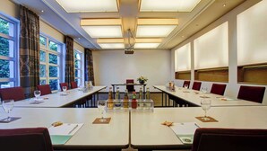 Un salón de conferencias con una larga mesa, sillas y un proyector.
