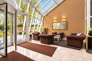A modern interior with a glass ceiling, leather sofas, a wooden coffee table, and a large mirror. - Hotel Noris City Nürnberg (Nuremberg)