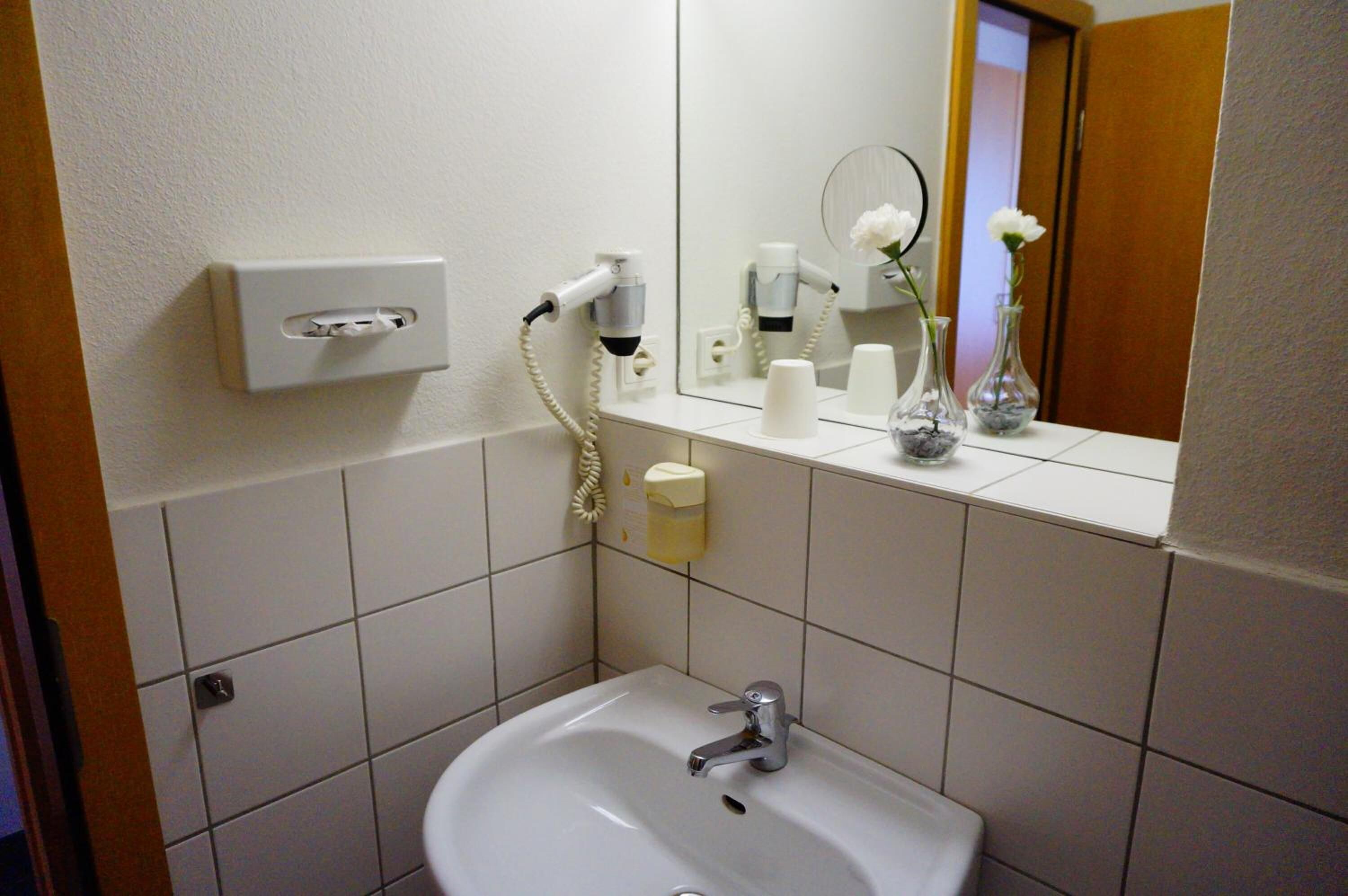 Un baño con lavamanos, espejo y artículos de aseo.