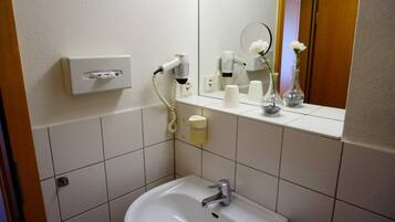 Un baño con lavamanos, espejo y artículos de aseo.
