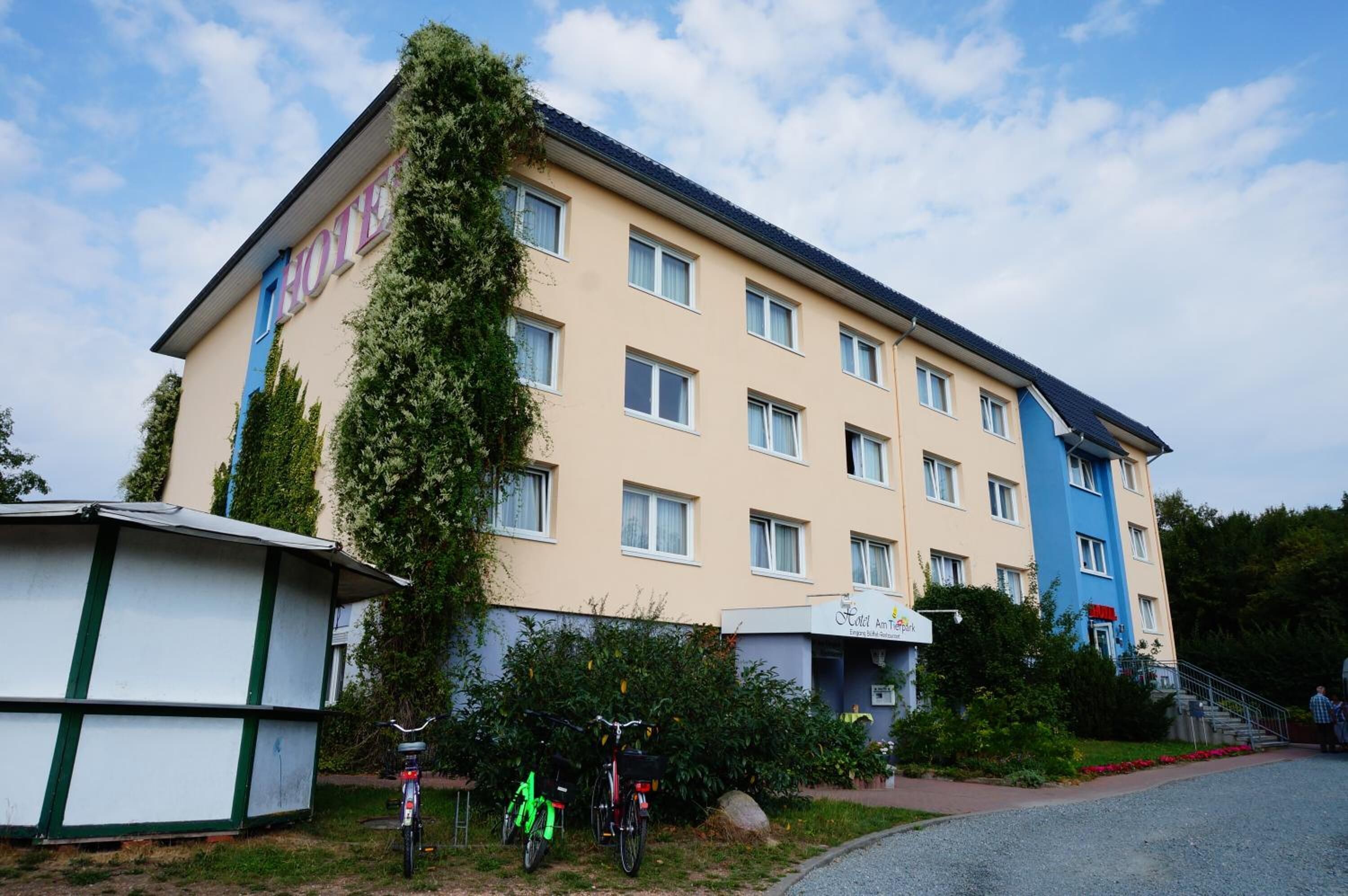 A multi-story hotel with a flat facade, several windows, and a small outdoor seating area.